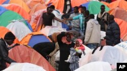 FILE - A Sudanese woman holds her child in front of a tent pitched outside the U.N. refugee agency headquarters in Amman, Jordan. The camp was raided by Jordanian troops Wednesday.