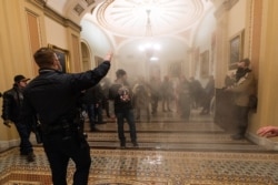 FILE - In this Jan. 6, 2021, file photo, smoke fills the walkway outside the Senate Chamber as violent rioters loyal to President Donald Trump are confronted by U.S. Capitol Police officers inside the Capitol in Washington.
