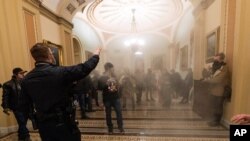 FILE - In this Jan. 6, 2021, file photo, smoke fills the walkway outside the Senate Chamber as violent rioters loyal to President Donald Trump are confronted by U.S. Capitol Police officers inside the Capitol in Washington. 