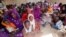 Women and children wait to participate in a vaccination campaign against meningitis at the community center in Al Neem camp for Internally Displaced People in El Daein, East Darfur, Sudan, October 8, 2012.