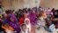 Women and children wait to participate in a vaccination campaign against meningitis at the community center in Al Neem camp for Internally Displaced People in El Daein, East Darfur, Sudan, October 8, 2012.