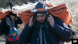 Migrants carrying their belongings walk from the Macedonian border into Serbia, near the village of Miratovac, Serbia, Jan. 19, 2016. 