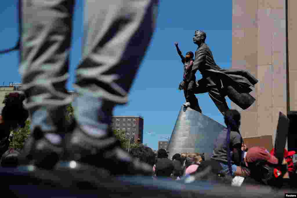Un manifestante alza el pu&#241;o junto a la estatua de Adam Clayton Powell Jr mientras las personas se manifiestan por la muerte del afroamericano George Floyd, en Nueva York, EE.UU.