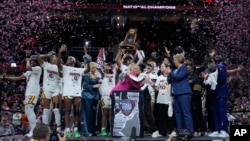 South Carolina players and coaches celebrate after the Final Four college basketball championship game against Iowa in the women's NCAA Tournament, April 7, 2024, in Cleveland. South Carolina won 87-75.