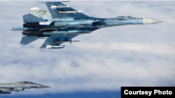 A Russian SU-27 Flanker aircraft banks away with a RAF Typhoon in the background. RAF Typhoons were scrambled on June 17 to intercept multiple Russian aircraft in international airspace as part of NATO’s ongoing Baltic Air Policing Mission. (UK Ministry o