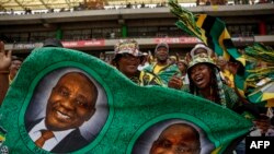 FILE - Ruling party supporters hold a fabric with a picture of South African President and president of the ANC Cyril Ramaphosa on during the 112th African National Congress Anniversary rally in Mbombela on January 13, 2024.