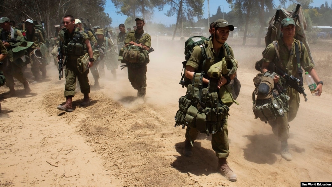 Israeli soldiers walk towards a staging area outside the Gaza Strip, July 18, 2014.