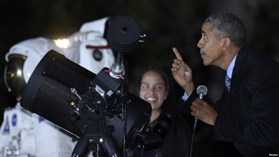 Presiden AS Barack Obama mengamati bulan sambil berbicara dengan Agatha Sofia Alvarez-Bareiro, murid SMA dari Brooklyn, New York, pada Malam Astronomi di Gedung Putih (19/10). (AP/Susan Walsh)