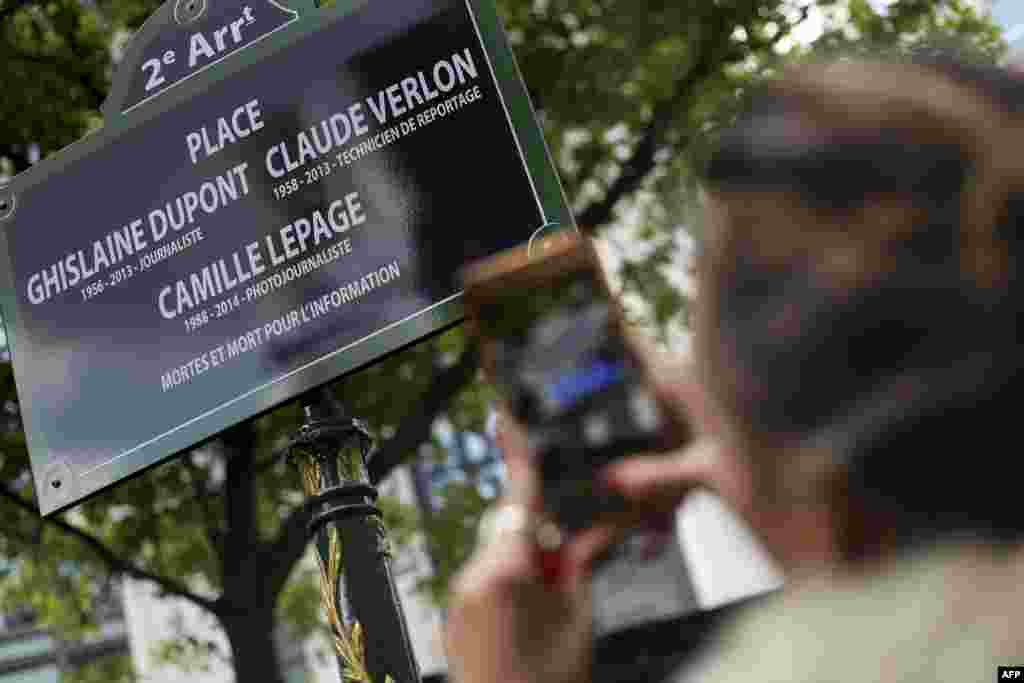 A woman in Paris, France, takes a picture of a street sign in tribute to Ghislaine Dupont and Claude Verlon, two French journalists killed on Nov, 2, 2013 in Mali, and French photojournalist Camille Lepage murdered on May 12, 2014 in Central African Republic.