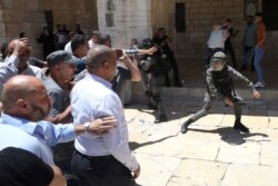 La policía israelí balancea sus porras contra los fieles musulmanes para evitar que se reúnan para las oraciones del viernes en la Mezquita de la Cúpula de la Roca. 14 de Mayo de 2021.