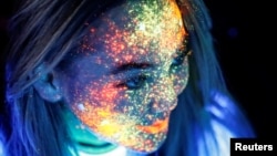 FILE - A participant with her face decorated with fluorescent paint smiles before the YARKOcross Night Edition colour run race in Almaty, Kazakhstan September 15, 2018. (REUTERS/Shamil Zhumatov)