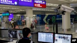 FILE - An officer monitors passengers arriving at Hong Kong International airport in Hong Kong, Jan. 4, 2020.
