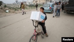 A Palestinian boy carries an aid box provided by UNRWA, amid a ceasefire between Hamas and Israel, in Gaza City, Feb. 3, 2025. 