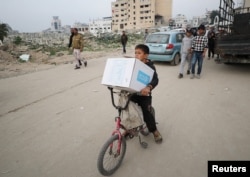 Seorang anak laki-laki Palestina membawa kotak bantuan yang disediakan oleh UNRWA, di tengah gencatan senjata antara Hamas dan Israel, di Kota Gaza, 3 Februari 2025. (Dawoud Abu Alkas/REUTERS)