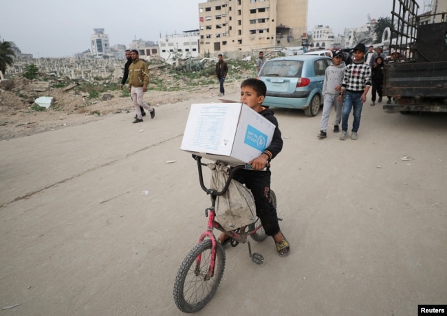 Seorang anak laki-laki Palestina membawa kotak bantuan yang disediakan oleh UNRWA, di tengah gencatan senjata antara Hamas dan Israel, di Kota Gaza, 3 Februari 2025. (Dawoud Abu Alkas/REUTERS)