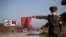 FILE - A public security officer uses a red flag to stop a taxi for disinfection as part of preventative measures against the COVID-19 coronavirus, on a road at the entrance to Wonsan, Kangwon Province, North Korea, Oct. 29, 2020.