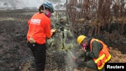 Dr. Jessica Ball of USGS, a geologist and volcanologist who does research at the US Geological Survey and Dr. Rick Hazlett (R) of University of Hawai'i at Hilo, are measuring temperatures in a crack near fissure 10 in the Leilani Estates Subdivision in Hawaii, U.S., June 8, 2018. (Alex Demas/USGS/Handout via REUTERS)