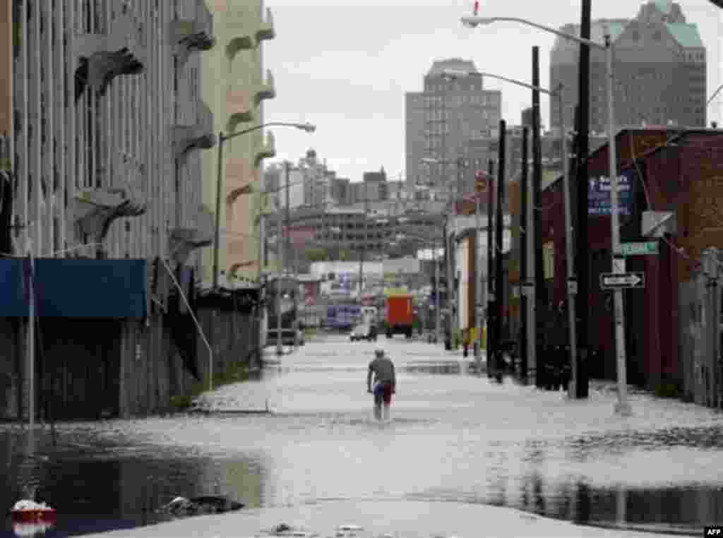 A police officer is parked at the end of a flooded street in Brooklyn, New York, Sunday, Aug. 28, 2011. Seawater surged into the streets of Manhattan on Sunday as Tropical Storm Irene slammed into New York, downgraded from a hurricane but still unleashing