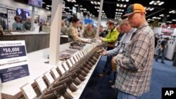FILE - A man looks at cases of firearms in the halls of the Indianapolis Convention Center, April 25, 2019, where the National Rifle Association held its 148th annual meetings.