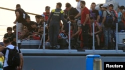 Migrants are seen onboard an Italian Coast Guard vessel following a rescue operation at the port on the Greek island of Kos, Aug. 16, 2015. 