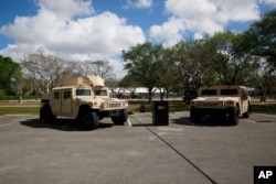 Vehicles are parked in front of where the National Guard is preparing for drive-through COVID-19 testing at C.B. Smith Park, March 19, 2020, in Pembroke Pines, Fla.
