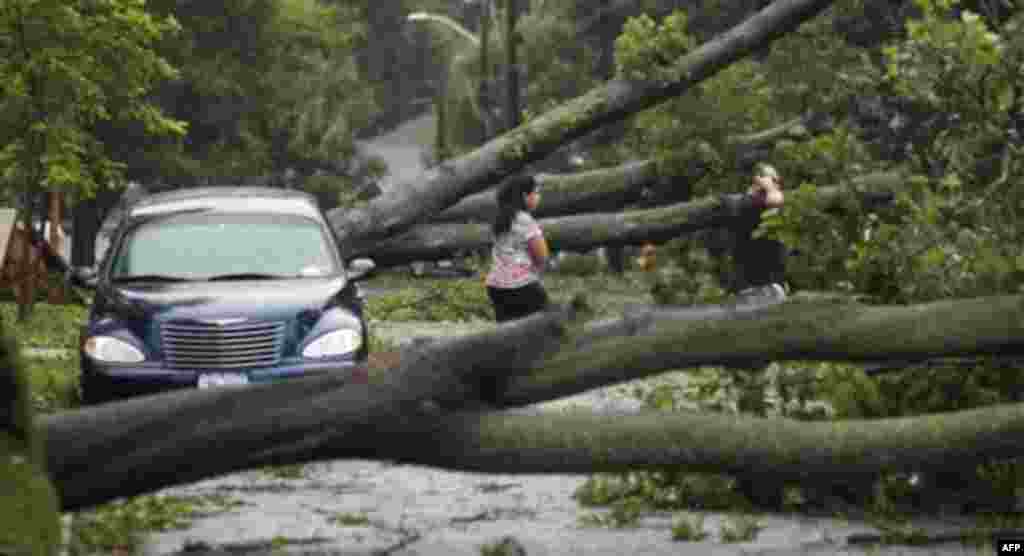 Two residents walk on their road which was not passable after the effects of Hurricane Irene dropped trees in their neighborhood in Massapequa, N.Y., on Long Island, Sunday, Aug. 28, 2011. (AP Photo/Charles Krupa)