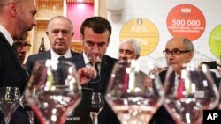 FILE - French President Emmanuel Macron drinks wine during a visit to the International Agriculture Fair (Salon de l'Agriculture) at the Porte de Versailles exhibition center in Paris, Feb. 22, 2020.