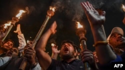 Protesters hold torches as they shout slogans against the government's Citizenship Amendment Bill during a demonstration in New Delhi, Dec. 11, 2019. 