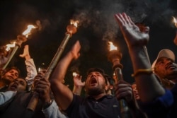 Protesters hold torches as they shout slogans against the government's Citizenship Amendment Bill during a demonstration in New Delhi, Dec. 11, 2019.