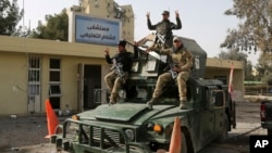 Members of Iraqi security forces flash victory signs outside al-Salam hospital after retaking the facility from Islamic State militants, in Mosul, Iraq, Jan. 10, 2017.