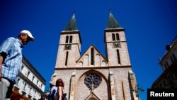 FILE - People walk past the Sacred Heart Cathedral in Sarajevo, Bosnia and Herzegovina, July 28, 2017.