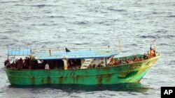 Para migran berada di dalam perahu menunggu bantuan dari Angkatan Laut Italia di perairan Capo Passero, Sisilia, Italia, 27 Maret 2013 (Foto: dok).