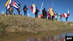 ARCHIVO - Migrantes que buscan asilo en Estados Unidos ondean banderas durante una misa binacional para recordar a los migrantes que han muerto intentando llegar a ese país en las orillas del Río Grande en Ciudad Juárez, estado de Chihuahua, México, el 9 de noviembre de 2024.