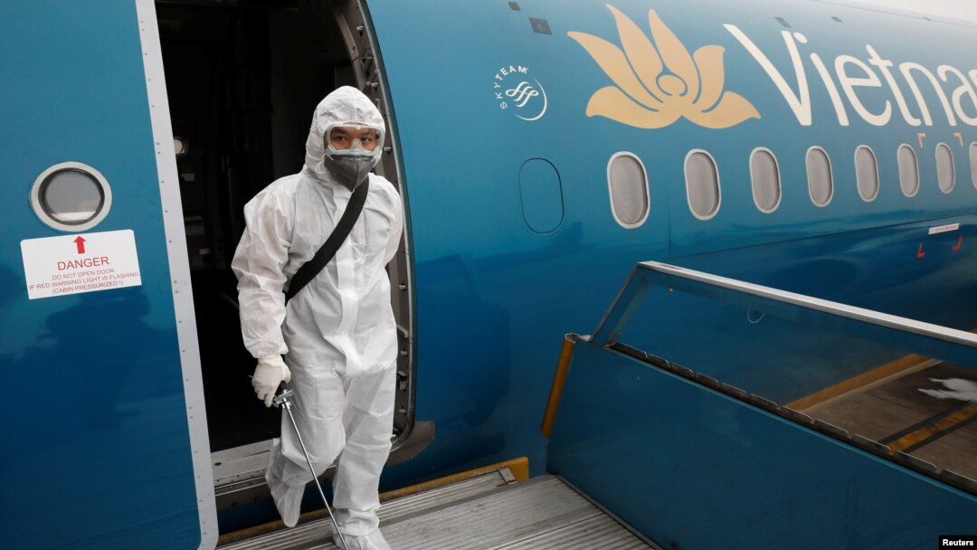 Nhân viên y tế xịt khử trùng máy bay của Vietnam Airlines. Một tiếp viên của hãng này đã trở thành người đầu tiên tại Việt Nam phải ra hầu toà vì tội vi phạm cách ly, gây lây lan COVID-19.