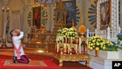 In this photo released by Bureau of the Royal Household, Thailand 's new king Maha Vajiralongkorn Bodindradebayavarangkun pays his respects to a portrait of the late Thai King Bhumibol Adulyadej and Thai Queen Sirikit at the Dusit Palace Dec.1, 2016.