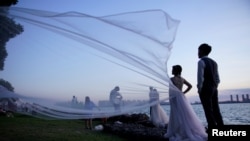 Sepasang penganti asal China berpose untuk foto pernikahan mereka di Suzhou, Jiangsu, China, pada 13 Agustus 2020. (Foto: Reuters/Aly Song)