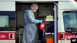 A medical worker wearing protective equipment sprays disinfectant at his ambulance after delivering a patient suspected of being infected with the coronavirus to the Pokrovskaya hospital in St.Petersburg, Russia, May 4, 2020. 