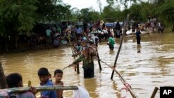 Muslim Rohingya melewati kawasan yang banjir untuk menemukan tempat penampungan alternatif karena kamp mereka yang terletak dekat kamp pengungsi Balukhali di Bangladesh, tergenang banjir, 19 September 2017. 