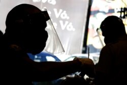 Barbers wear face shields, masks, and gloves for protection amid the COVID-19 pandemic while attending clients on the first day the shop was allowed to reopen, as restrictions ease in Brasilia, Brazil, July 15, 2020.