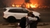 Personas se abrazan mientras evacúan luego de que los fuertes vientos alimentaron incendios forestales devastadores en el área de Los Ángeles. Foto captada en Eaton, Altadena, California, el 8 de enero de 2025.