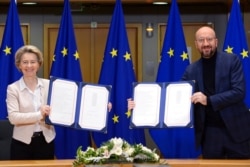 European Commission President Ursula von der Leyen, left, and European Council President Charles Michel show signed EU-UK Trade and Cooperation Agreements at the European Council headquarters in Brussels, Dec. 30, 2020.
