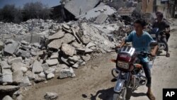 Syrians look at a destroyed house after it was hit by an air strike killing six Syrians in town of Tal Rifat on the outskirts of Aleppo, Syria, Aug. 8, 2012. 