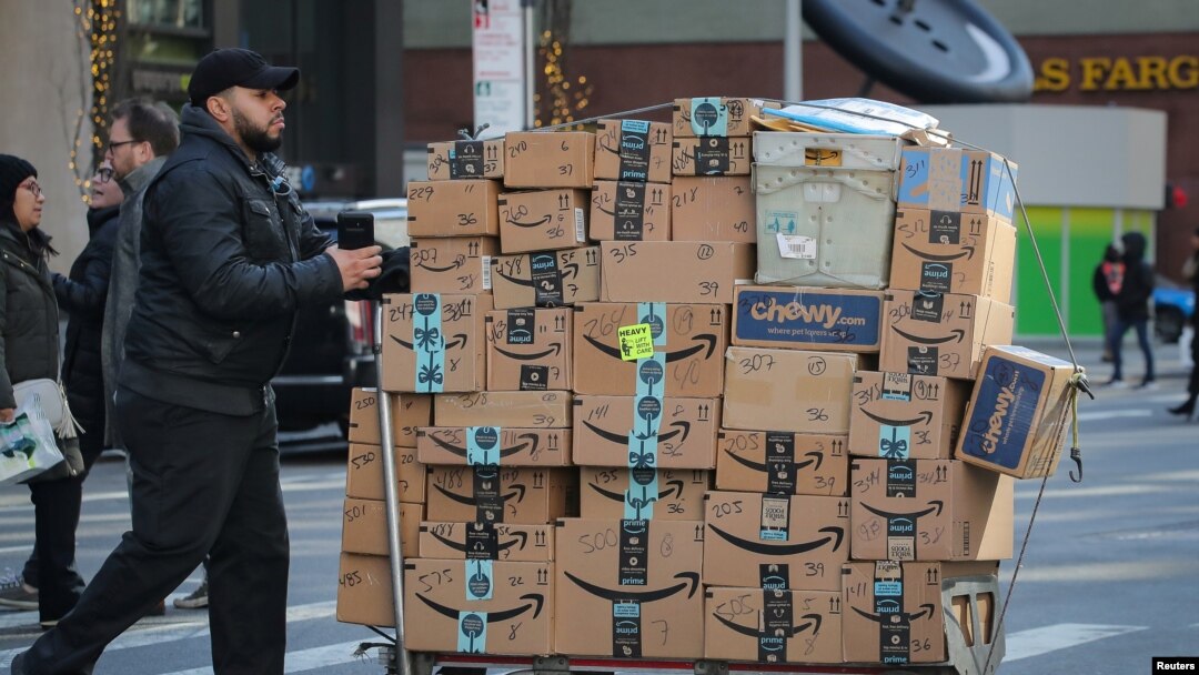 Seorang petugas layanan antar barang mendorong gerobak penuh kotak Amazon di New York City, AS, 14 Februari 2019. (Foto: dok).