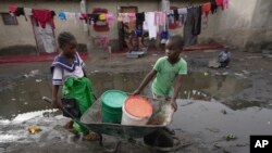 Des enfants vont chercher de l'eau à l'aide d'une brouette dans le township de Lilanda à Lusaka, en Zambie, le samedi 9 mars 2024. (AP Photo/Tsvangirayi Mukwazhi)