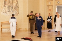 Raja Inggris Charles III dan Ratu Camilla berdiri setelah meletakkan karangan bunga di Monumen Perang Australia di Canberra, 21 Oktober 2024. (Brook Mitchell / POOL / AFP)