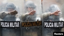 Military police officers stand guard as supporters of former Bolivian President Evo Morales take part in a protest in La Paz, Bolivia, Nov. 14, 2019.