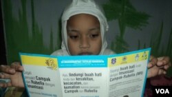 Seorang siswa SD membaca selebaran dari sekolah terkait imunisasi MR-Campak dan Rubella (Foto: VOA/Yudha).