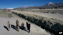 Soldados chilenos hablan con migrantes antes de trasladarlos a un refugio donde la policía hace registro de ellos, cerca de Colchane, Chile, el 1 de marzo de 2023. 