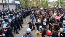 Petugas kepolisian membentuk barikade terhadap pengunjuk rasa dalam pawai May Day untuk memprotes potongan pensiun, penutupan sekolah, dan lambatnya upaya pemulihan dari bencana topan di San Juan, Puerto Rico, 1 Mei 2018 (foto: AP Photo/Carlos Giusti)