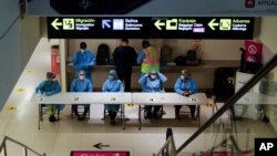 Health workers wait to revise arriving passengers' COVID-19 test results and administer tests to those who do not have one to show at Tocumen International Airport in Panama City, Oct. 12, 2020. 